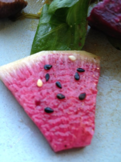 Slice of watermelon radish with black sesame "watermelon seeds"