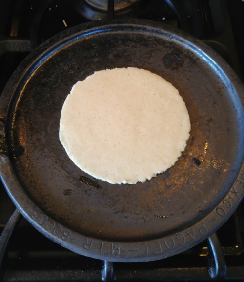 Freshly-pressed tortilla baking on the hot comal